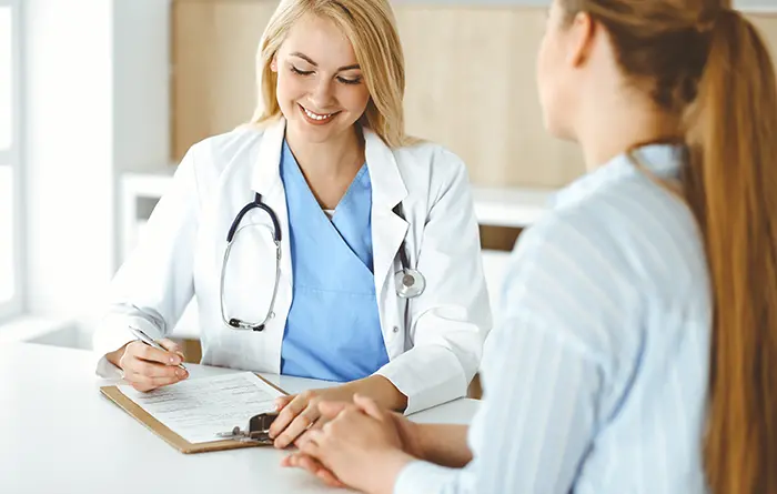 The doctor sits across from the patient and fills out the post-surgery questionnaire.